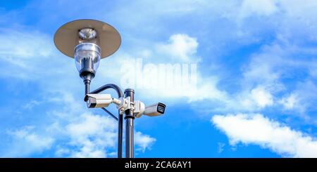 Two white surveillance cameras on the metal street light lamp post outdoor  Stock Photo