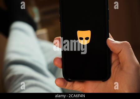 Grindr application on the smartphone in mans hand. Man laying and using application for dating and meeting. Social network concept, July 2020, Prague Stock Photo