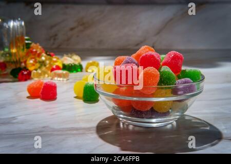 Granulated sugar coated candy gumdrops with spilled jar of gummy bears in background Stock Photo
