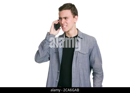 A young man in a Manatee shirt, black t-shirt and trousers, isolated on white, arguing with someone on the phone Stock Photo