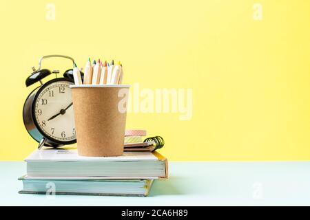 Back to school banner with black alarm clock, books and pencil. School supplies, other elements in yellow mint empty background with copy space Stock Photo