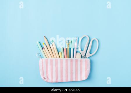 Flat lay of modern bright blue office desktop with school supplies on table around empty space for text in pencil case. Top view Back to school Stock Photo