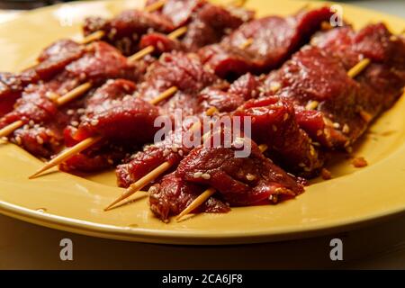 Raw marinating Korean BBQ beef Bulgogi kebab skewers with sesame seeds Stock Photo