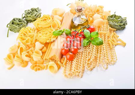 A group of different types of Italian pasta. Pasta with fresh tomatoes, basil and olive oil on light shabby rustic background, top view, border. Pasta with ingredients for cooking. Italian food Stock Photo