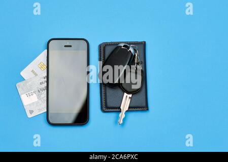 Car keys, mobile phone and credit cards on blue background. Top view. Do not forget to take car keys, money and smartphone before leaving home Stock Photo