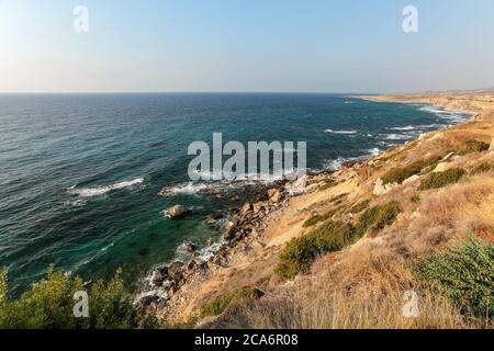 Evening sun shines on rough coast of Mediterranean Sea in Karpass region of Northern Cyprus Stock Photo