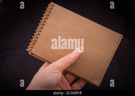 White notebook in hand on  a black color background Stock Photo