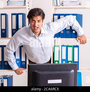 The young male employee working in the office Stock Photo