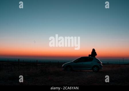 young man sitting on car at blue hour Stock Photo