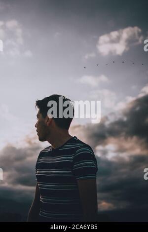 young adult man looking at the horizon between the clouds Stock Photo