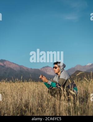 young man sitting in the field next to Andes mountains Stock Photo