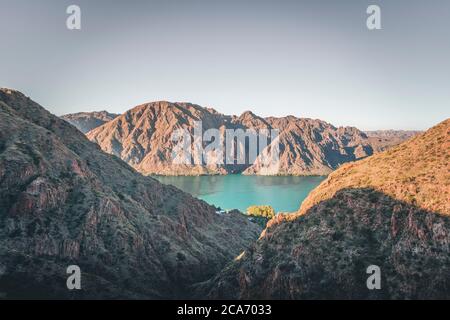 small house located between hills next to a reservoir Stock Photo