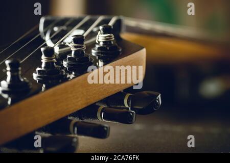 Closeup tuning key on the headstock of the black electric guitar in dark background and morning light. Copy space on the right. Concept of good memory Stock Photo