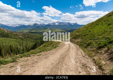 Last Dollar Road above a landscape of the snow-capped San Juan Mountains and aspen groves near Telluride, Colorado Stock Photo