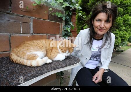 Neustrelitz, Germany. 14th July, 2020. Manuela Jeschke, founder of the private animal protection initiative Katzenparadies Neustrelitz, strokes a cat in the outdoor area. More than 50 velvet paws currently live in the cat paradise. There are no bars for healthy, adult and neutered animals here. You can freely choose between the cat living rooms in the house and the garden, which looks like a miniature children's playground. Only those who are new, sick or still too small for outside live in enclosures for the time being. Credit: Bernd Wüstneck/dpa-Zentralbild/dpa/Alamy Live News Stock Photo