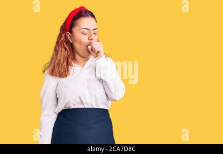 Young latin woman wearing waitress apron feeling unwell and coughing as symptom for cold or bronchitis. health care concept. Stock Photo