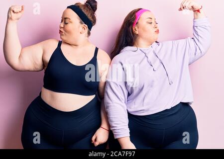 Young plus size twins wearing sportswear showing arms muscles smiling proud. fitness concept. Stock Photo
