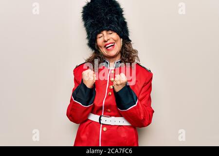 Middle age beautiful wales guard woman wearing traditional uniform over white background celebrating surprised and amazed for success with arms raised Stock Photo