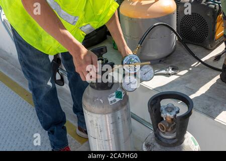 Denver, Colorado - A technician works on the air conditioning system on the roof of an affordable housing building under construction. Stock Photo