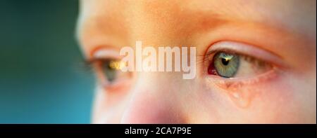 Cry baby with sky blue eyes, close up. Little tender boy crying. Eye drop, tear drop of little sweetheart kid. Emotional child miss his mom. Childhood Stock Photo