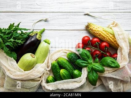 Fresh vegetables in eco cotton bags on table in the kitchen.  Fresh vegetables from market. Zero waste shopping concept. Stock Photo