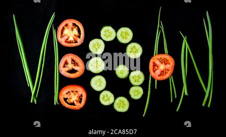 Word VEGAN made of green onion cucumber and tomato, healthy vegan eating, low calorie diet Stock Photo