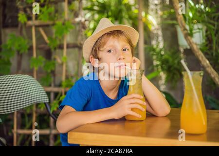 cute little boy drinking orange juice in cafe Stock Photo