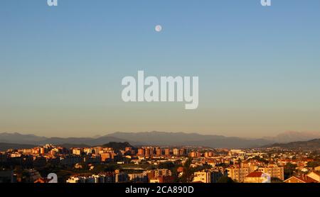 Late afternoon summer view towards mountains and the moon high in a blue sky looking west towards the Picos de Europa mountain range from Santander Stock Photo