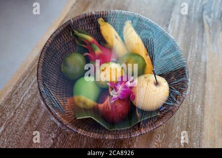 Wooden complimentary basket of wrapped fruits- contains banana, orange, dragon fruit and Chinese pear Stock Photo