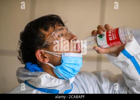 (200805) -- URUMQI, Aug. 5, 2020 (Xinhua) -- Volunteer Ekebar Emet drinks water at a community in Tianshan District of Urumqi, northwest China's Xinjiang Uygur Autonomous Region, Aug. 3, 2020. Ekebar Emet, a 21-year-old junior student, comes from Bachu County of Xinjiang. He went to the Dongcaiyuan Community in Tianshan District of Urumqi City to practise for one year on June 3. The sudden COVID-19 resurgence in Xinjiang immediately transformed Ekebar from a university intern to a volunteer at the frontline of epidemic prevention and control. Ekebar publicized epidemic prevention measu Stock Photo