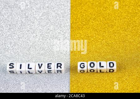 silver  and gold words formed by white dices with black letters  laying on silver and golden background, image split in two halves Stock Photo