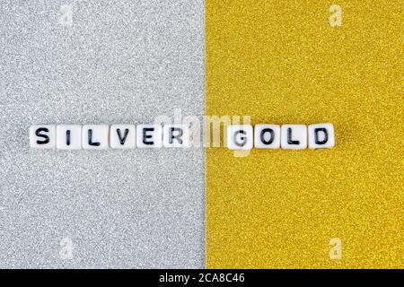 silver  and gold words formed by white dices with black letters  laying on silver and golden background, image split in two halves Stock Photo