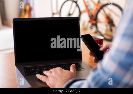 Laptop with blank black screen and male hands on the keyboard. Stock Photo