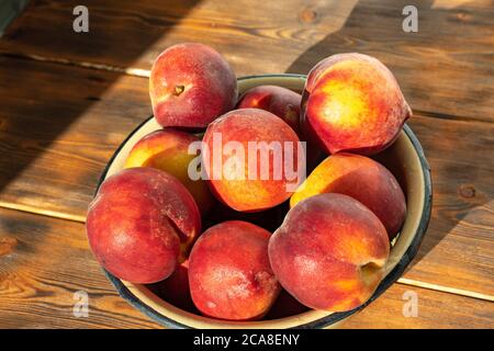 ripe peaches in an iron bowl on a wooden background Stock Photo