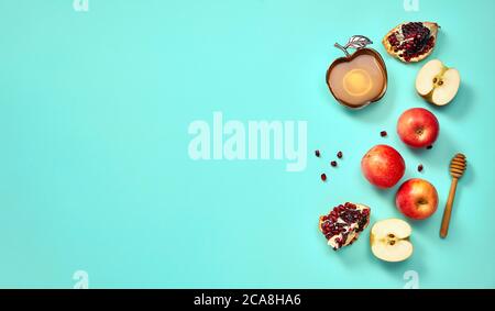 Rosh hashanah (jewish New Year holiday) concept. Traditional symbols. Apples, honey and pomegranates on a turquoise background. Stock Photo
