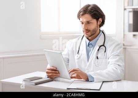 Young doctor using digital tablet for work in office Stock Photo