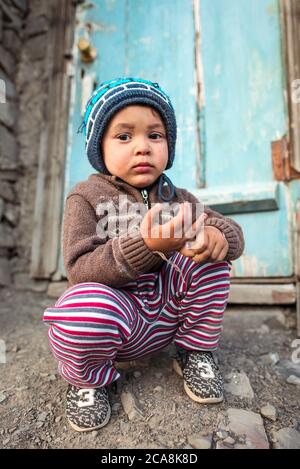 Xinaliq / Azerbaijan - July 8, 2019: portrait of little boy with woolen hat on streets of stone houses village Stock Photo