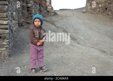 Xinaliq / Azerbaijan - July 8, 2019: portrait of little boy with woolen hat on streets of stone houses village Stock Photo