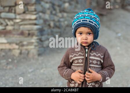 Xinaliq / Azerbaijan - July 8, 2019: portrait of little boy with woolen hat on streets of stone houses village Stock Photo