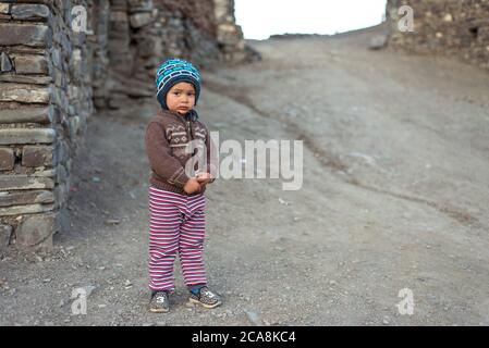 Xinaliq / Azerbaijan - July 8, 2019: portrait of little boy with woolen hat on streets of stone houses village Stock Photo