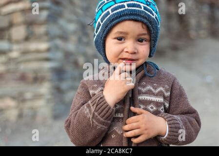 Xinaliq / Azerbaijan - July 8, 2019: portrait of little boy with woolen hat on streets of stone houses village Stock Photo