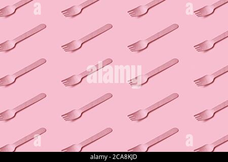 Plastic-free, zero waste, eco friendly disposable cutlery made of wood. Wooden fork flat lay, seamless pattern. Modern stylish design in trendy pink. Stock Photo