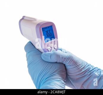 Body Temperature infrared forehead Thermometer celsius Doctor Hand with blue glove isolated on white background Stock Photo