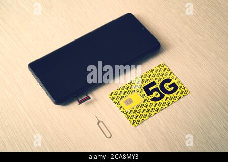Broadband 5G mobile communication technology concept SIM card tray, dual SIM card slot with two nano SIM cards on wooden background. Stock Photo