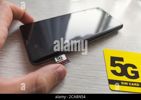 Replacing 4G SIM card with a high speed 5g SIM card close up on the store's wooden table Stock Photo