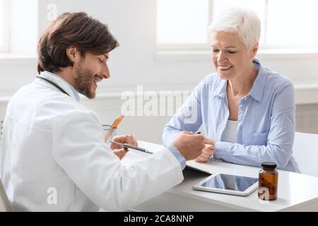 Friendly doctor telling treatment prescription to senior patient Stock Photo