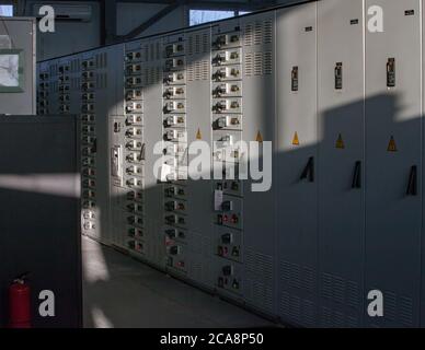 Grey electric cabinet with switchers and lamp indicators half in shadow and light. Stock Photo