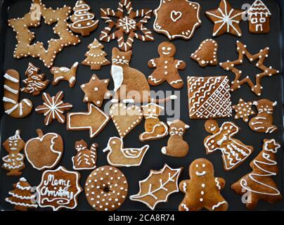 Gingerbread cookies decorated with royal icing on baking sheet. Christmas food. Stock Photo