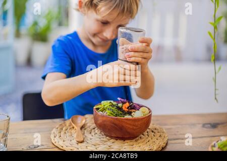 Boy eating Poke bowl with shrimp, corn, avocado, ginger and mushrooms Stock Photo