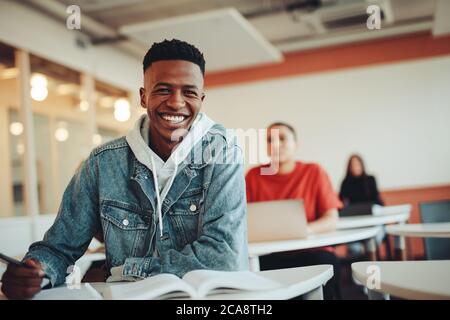 African student sitting in classroom. Male student smiling during the lecture in high school classroom. Stock Photo